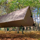 DD Tarp Medium set up in an A-frame over a hammock in the woods, ideal for protection during camping.